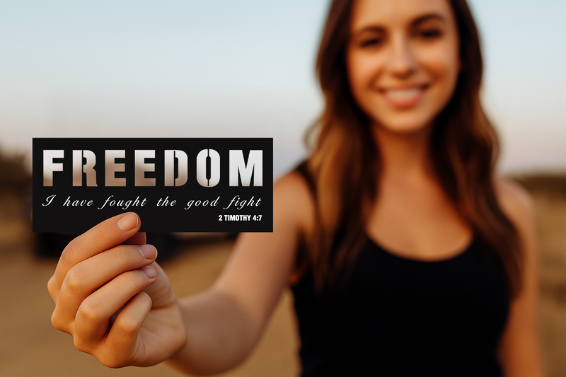 Woman holding a sign with 'FREEDOM' and a Bible verse against a blurred natural background